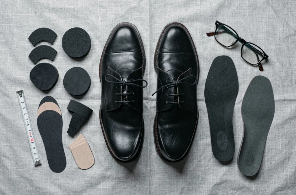 Flat lay de chaussures Oxford noires trop grandes avec semelles intérieures et talonnettes pour corriger le glissement au talon